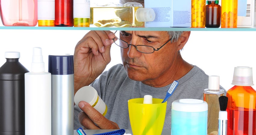 Unshaven Middle aged man reading a prescription label in front o