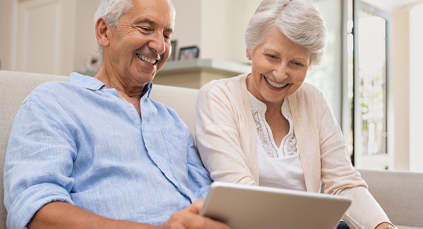 Happy elderly people spending time together at home, using gadgets